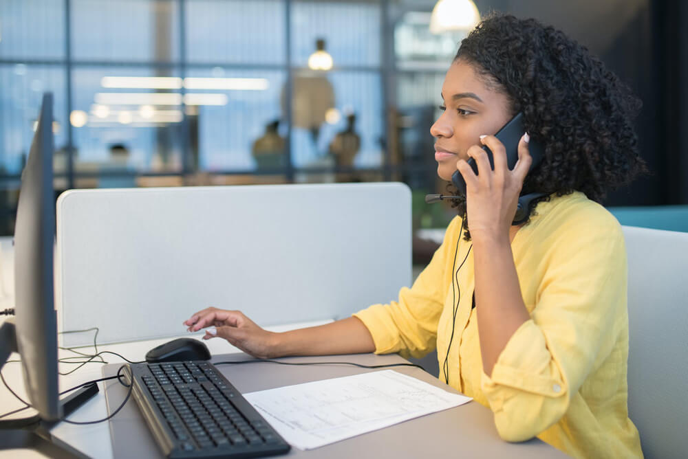 black woman on the phone in front of computer screen