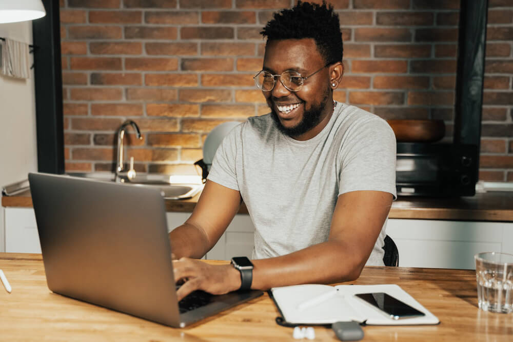 happy black man making notes on laptop