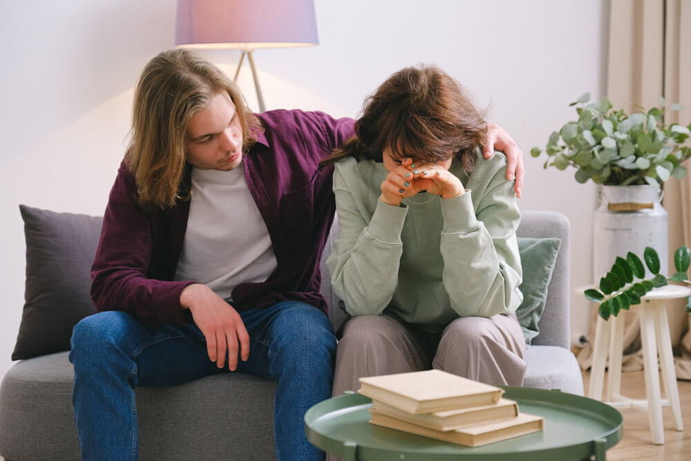 man comforting crying wife on couch