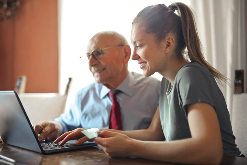 young woman helping elderly man with computer young woman helping elderly man with computer